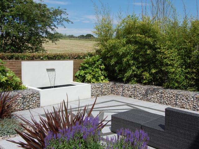 Contemporary garden with cedar battens, gabions filled with cobbles and a stainless steel water blade