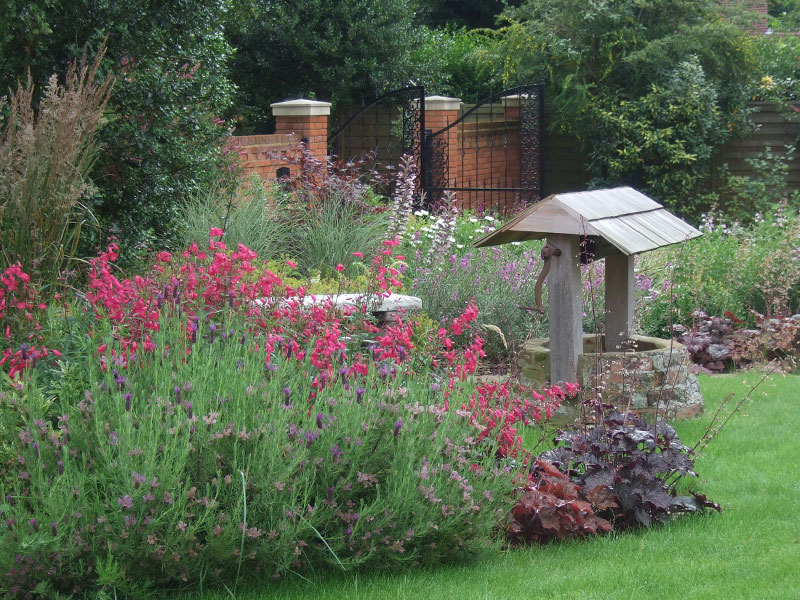Relaxed perennial planting surrounds a restored well