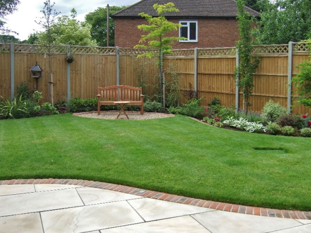 Traditional garden with brick edged patio and curving borders