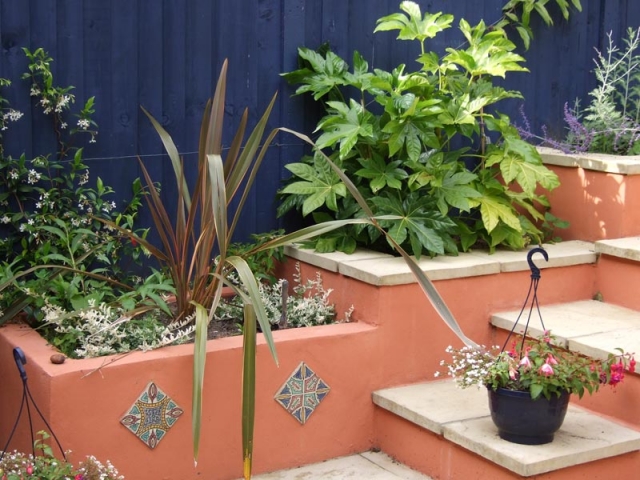 Lush planting in built-in painted planters set off by a deep blue fence