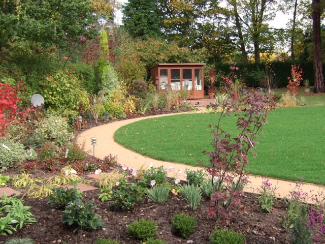 Deep mixed borders and sel-binding gravel path surround a central lawn