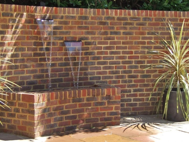 Recycling water feature with two stainless steel water blades set into brick wall