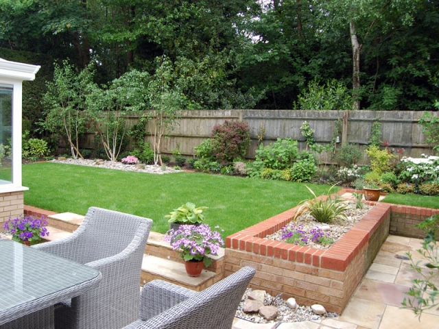 Sunken patio, raised lawn and trio of silver birches