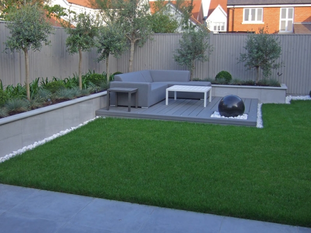 Central lawn with decked seating area, water feature and raised planting beds