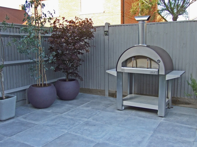 Grey porcelain paving with stainless steel pizza oven and large Cadix planters