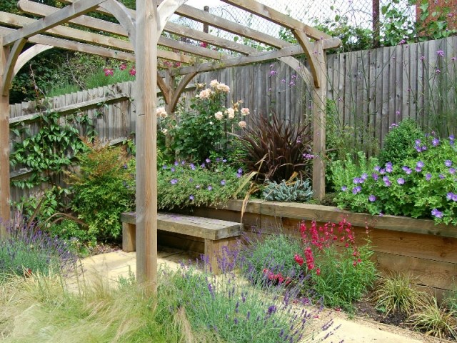 Sleeper terrace with built-in bench under pergola surrounded by flowers