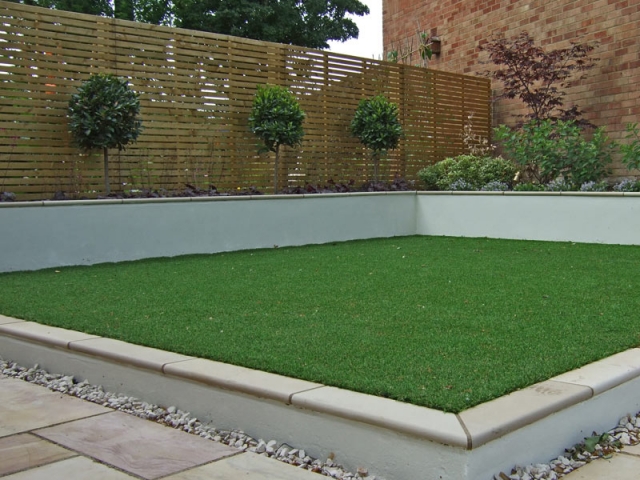 Contemporay garden with horizontal slatted fence and artificial grass