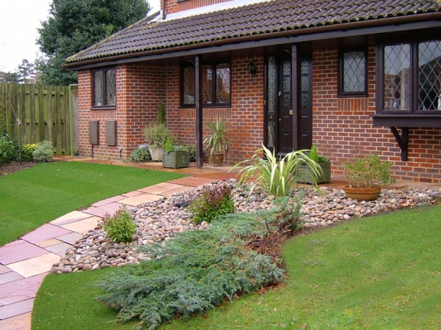Front garden with modak sandstone path and planting through cobbles.