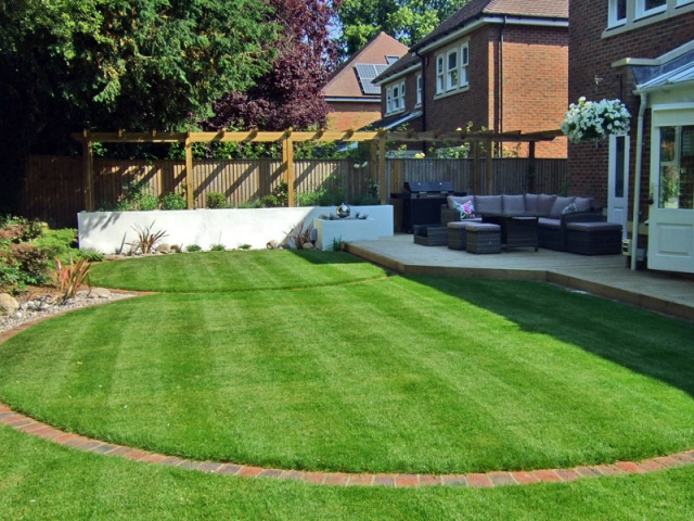 Contemporary garden with deck, rendered raised bed, stainless steel water feature and rattan lounge