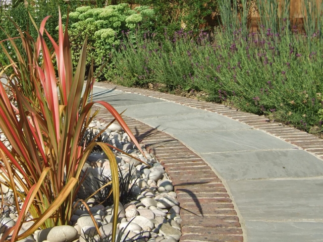 Curved sandstone path with red brick edging