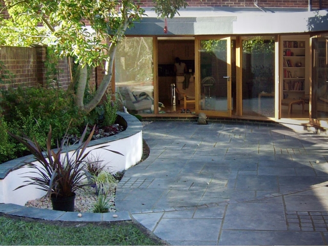 Curving rendered wall with black limestone coping stones